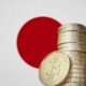 A stack of Bitcoin coins with the Japanese flag in the background.