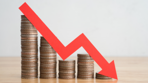 Item ID: 2127109961 Bar graph of coin stack and red graph trending down with white background on the wall on wooden table copy space.  Economic recession crisis, inflation, stagflation, business and financial loss concept., penny stock, sale.  Actions to avoid